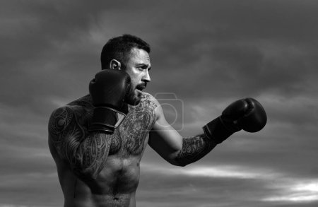 Photo for Boxer fighter training outdoors. Sportsman muay thai boxer fighting in gloves. Sporty man during boxing exercises. Strength, attack and motion concept. Boxing training outside. Muscular man body - Royalty Free Image