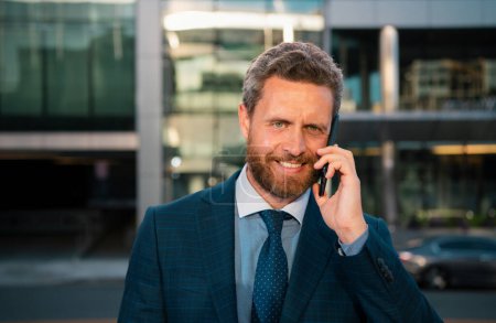 Photo for Businessman talking on phone. Portrait of cheerful Business man office worker talking on mobile phone while standing near modern office - Royalty Free Image