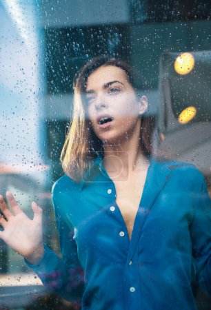 Foto de Retrato de mujer joven al aire libre. Concepto pensativo. Mujer en un café mientras mira a través del cristal de la ventana - Imagen libre de derechos