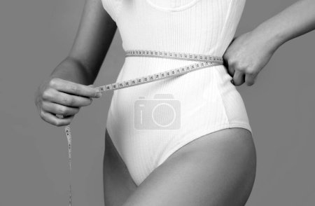 Photo for Attractive caucasian woman measuring her waist isolated background. Trained belly with measuring tape - Royalty Free Image