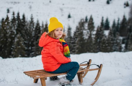 Foto de Niño disfrutando de un paseo en trineo. Niño en trineo. El niño juega afuera en la nieve. Invierno, vacaciones y Navidad - Imagen libre de derechos