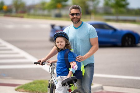 Photo for Little kid learning to ride bicycle with father on on summer holiday. Father teaching son cycling. Father and son learning to ride a bicycle at Fathers day. Father support and helping son. Child care - Royalty Free Image