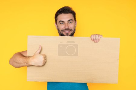 Photo for Good choice, recommend like concept with copy space. Man with thumb up and blank banner ad, on studio background. Portrait of man holding empty blank poster - Royalty Free Image