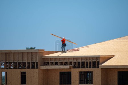 Téléchargez les photos : Toit en bois. Réparation des toits. Travailleur de toiture installer un nouveau toit sur le toit. Grandes poutres de toit. Une poutre de toitures en bois de construction à partir de cadres de fermes pour la maison de bâton nouvellement construite - en image libre de droit