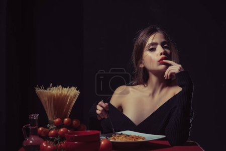 Téléchargez les photos : Manger des pâtes spaghetti. Portrait de jeune femme mangeant des pâtes spaghetti. Manger des pâtes. Une femme mange des spaghettis avec de la sauce. Bonnes pâtes. Une fille mange des spaghettis. Une saine alimentation. Cuisine sexy. Lécher les doigts bouche - en image libre de droit