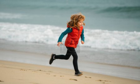 Téléchargez les photos : Un enfant court au bord de la mer. Des enfants qui courent sur la plage. Enfant coureur joggeur courir dans la nature. Mode de vie sain et actif des enfants - en image libre de droit