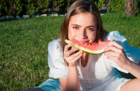 Téléchargez les photos : Portrait jeune femme heureuse tient tranche de pastèque. Belle jeune femme avec pastèque dans le parc le jour ensoleillé - en image libre de droit