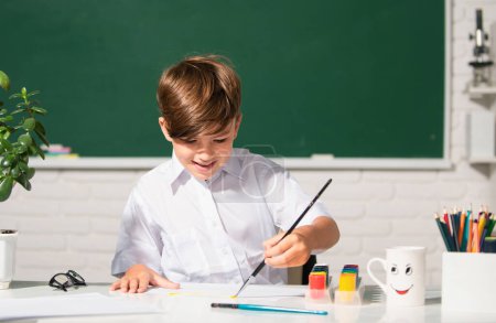 Téléchargez les photos : Child boy at school draws with paints. Kids artist creativity. kid learning painting - en image libre de droit