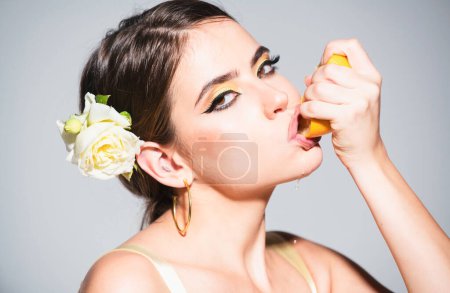 Photo for Sexy woman with stylish makeup on beautiful face squeezing juice from fresh orange, lick orange juice. Pretty attractive funny comic positive woman having pieces of orange - Royalty Free Image