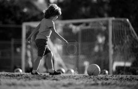 Téléchargez les photos : Enfant garçon jouant au football sur le terrain de football. Un gamin qui joue au foot. Jeux de ballon actif - en image libre de droit