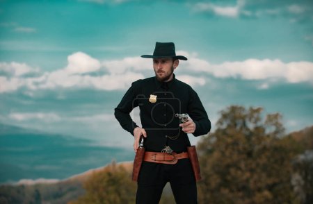 Foto de Sheriff o alguacil. Oeste americano, salvaje oeste con vaquero. Tipo serio con arma de revólver al aire libre - Imagen libre de derechos
