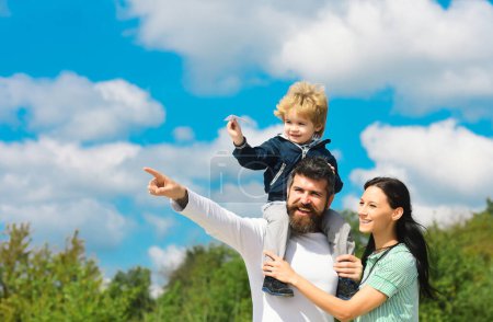 Photo for Happy family having fun, parents and little child playing together with toy paper plane. Cheerful son with father and mother enjoying spending time. Parents with child enjoying playing, freedom to - Royalty Free Image