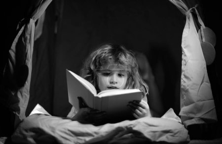 Foto de Libro de lectura infantil. Niños, hora de dormir. Niño leer libro en la cama - Imagen libre de derechos