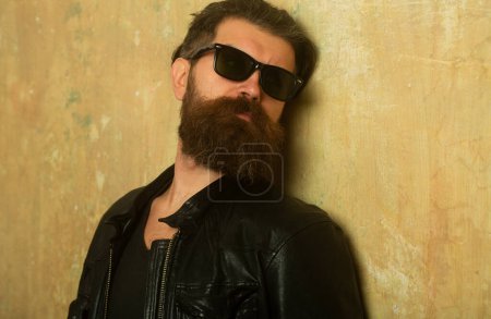 Téléchargez les photos : Portrait d'un bel homme. Hipster barbu sur fond mural beige - en image libre de droit