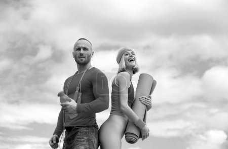 Téléchargez les photos : Sporty funny couple with dumbbell outdoors. Athletic young happy couple holding dumbbells and fitness mat outdoor - en image libre de droit