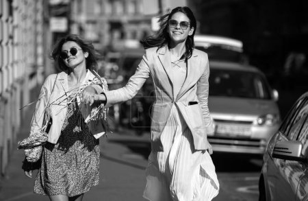 Foto de Emocionadas mujeres felices caminando juntas en la calle. Feliz hermosa mujer amigos en vestido de moda caminando y corriendo alegre y alegre sonriendo en la ciudad - Imagen libre de derechos