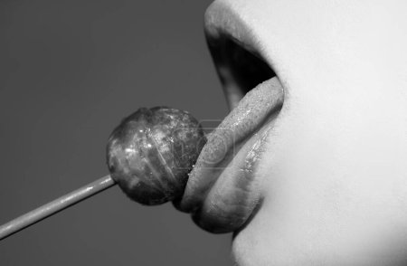 Photo for Licking tongue lips. Girl with sexy mouth eating chupa chups close up. Woman lips sucking lollypop. Woman holding lollipop in mouth, close up. Red lips, sensual and sex shop concept - Royalty Free Image