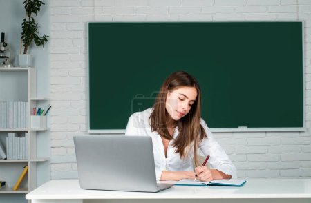 Téléchargez les photos : Étudiante travaillant sur un ordinateur portable en classe, se préparant à un examen - en image libre de droit