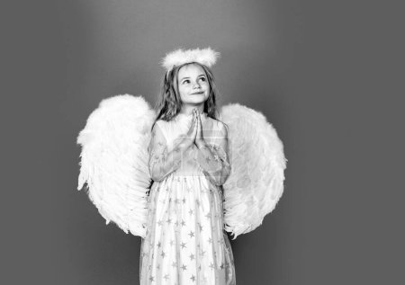 Téléchargez les photos : Enfant ange prière. Enfant à caractère angélique. Petite fille portant costume d'ange robe blanche et ailes de plumes. Consept d'enfant innocent - en image libre de droit