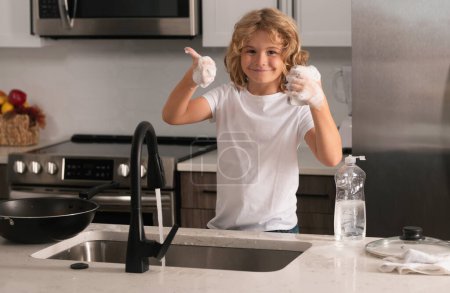 Téléchargez les photos : Lave-vaisselle pour enfants avec eau et savon près de l'évier dans la cuisine - en image libre de droit