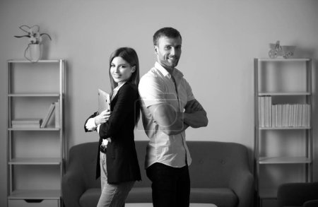 Foto de Equipo de negocios exitoso Colaboradores de negocios de pie en la oficina. Dos jóvenes trabajadores de negocios con portátil - Imagen libre de derechos