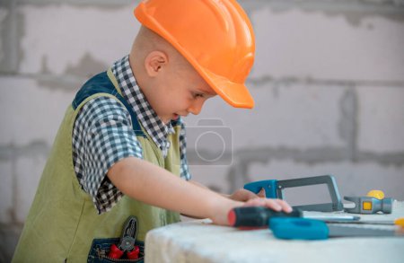 Photo for Child in helmet is construction worker. Foreman kid work in the hard hat making repairs. Childhood development. Little builder engineer. Improve your childhood. Kids building and repair - Royalty Free Image