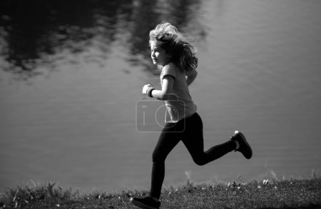 Téléchargez les photos : Enfant garçon courant dehors. Enfant coureur joggeur courir dans la nature. Bonjour, jogging. Mode de vie sain et actif des enfants - en image libre de droit