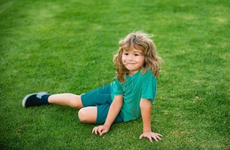 Photo for Happy little boy laying on the grass in park - Royalty Free Image