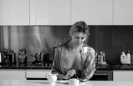 Foto de Pecho desnudo. Hermosa mujer beber café cerca de la mesa en la cocina en casa. Ama de casa en la cocina por la mañana - Imagen libre de derechos
