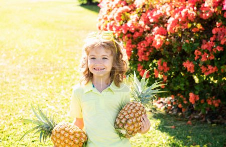 Foto de Retrato de un niño pequeño al aire libre en verano. Sonriente lindo divertido chico sosteniendo una piña - Imagen libre de derechos