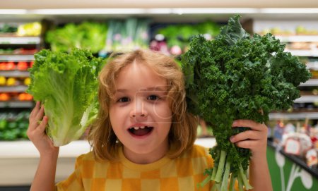 Téléchargez les photos : Enfant avec des légumes à la laitue. Petit enfant choisissant de la nourriture dans une épicerie ou un supermarché - en image libre de droit