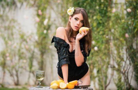 Foto de Mujer joven comiendo pera en el jardín al aire libre. Comida vegetariana saludable, atención médica. Sexy mujer joven y saludable comida vegetariana, frutas - Imagen libre de derechos