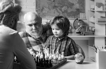 Téléchargez les photos : Portrait grand-père et petit-fils jouant aux échecs. Relations familiales entre le grand-père, le père et le fils. Grand-père enseignant écolier élève - en image libre de droit