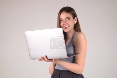Foto de Estudiante feliz. Mujer Estudiante en camiseta blanca sosteniendo portátil y portátil, aislado sobre fondo gris. Estudiante posando en estudio. Retrato del estudiante haciendo videollamadas. Tiempo de los estudiantes - Imagen libre de derechos