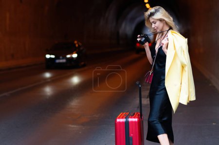Foto de Traveler tourist woman in fashion dress with suitcase. Sexy girl with travel bag ready to travel on vacation - Imagen libre de derechos