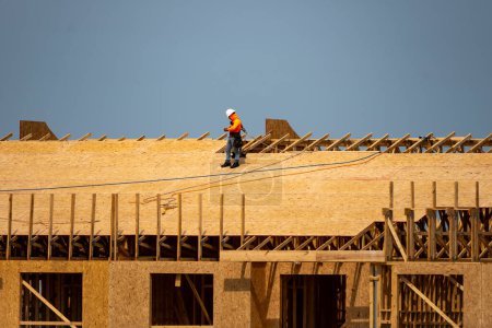 Photo for House roof. Roofing construction. Roofer using air nail. Roofing tiles of the new roof under construction building. Repairing building roof. Repair roofs, install roofing, renovate house. Frames roof - Royalty Free Image