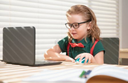 Foto de Alumno de escuela inteligente niño virtual aprendizaje a distancia en línea, viendo lección de clase digital remota, mirando el ordenador portátil estudiando en casa - Imagen libre de derechos