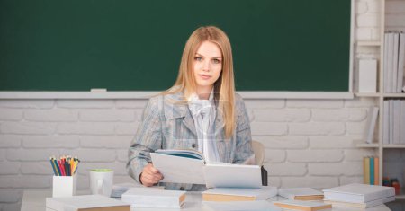 Photo for Female student in university, school education, Young woman study in college classroom. Serious student reading book on blackboard background with copy space - Royalty Free Image