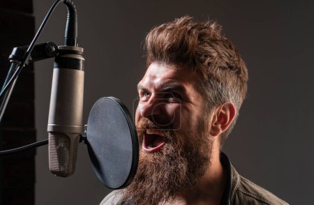 Photo for Singing man in a recording studio. Expressive bearded man with microphone. Closeup portrait - Royalty Free Image