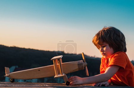 Photo for Dreams of flight. Child playing with toy plane against the sky. Dreams of travels. Little dreaming child with a toy airplane plays outdoors. Cute kids face - Royalty Free Image