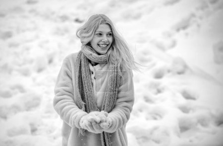 Téléchargez les photos : Fille jouant avec la neige lancer une balle pendant les vacances d'hiver. Une femme heureuse tient la boule de neige dans ses mains. Portrait d'une femme heureuse en hiver. Fille gaie en plein air - en image libre de droit