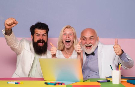 Photo for Excited business people sitting at the office table with group of colleagues, working on laptop computer. Business people enjoying success - Royalty Free Image