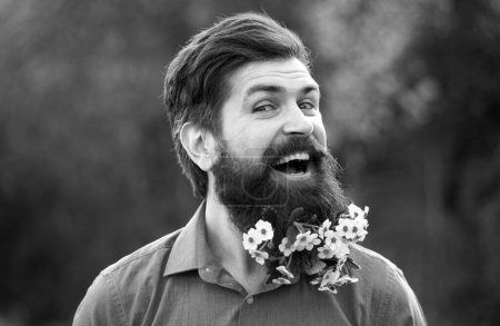 Téléchargez les photos : Barbe fleurie. Homme barbu avec des fleurs de printemps dans la barbe - en image libre de droit
