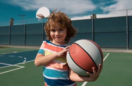 Foto de Lindo niño sosteniendo una pelota de canasta tratando de hacer un marcador. Deporte para niños - Imagen libre de derechos