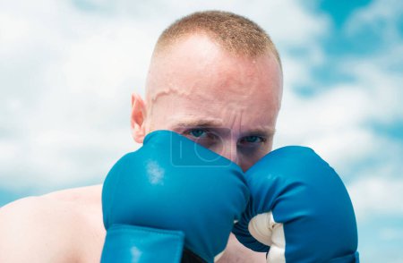 Téléchargez les photos : Portrait rapproché d'un boxeur pratiquant des coups de poing en boxe. Poinçon de boxe dans des gants de boxe. Homme sportif pendant l'exercice de boxe. Force et motivation - en image libre de droit