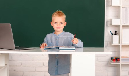 Photo for Pupil near chalkboard during lesson at primary school. School child student learn lesson sitting at desk studying - Royalty Free Image