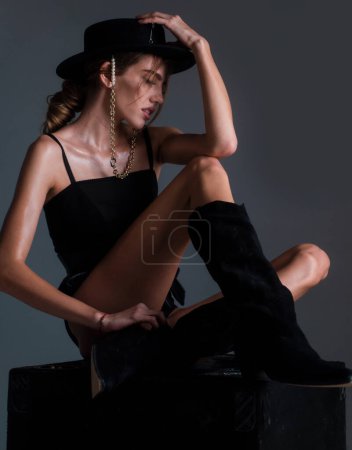 Photo for Beautiful sensual woman fashion model in trendy clothes wearing a black round hat. Sexy female posing in studio. Beautiful high fashion female model with beauty face. Fashion boutique advertising - Royalty Free Image