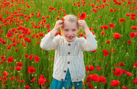 Téléchargez les photos : Jolie petite fille sur un champ de pavot, en plein air. Enfant fille dans un champ de coquelicots rouges aime la nature. Petite fille dans le champ de pavot. Conception printemps enfants - en image libre de droit