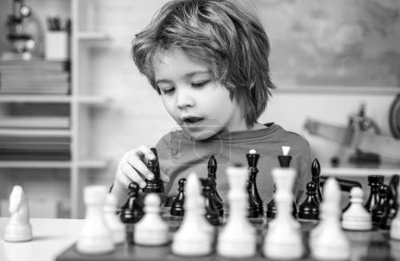 Téléchargez les photos : Enfant jouant aux échecs. Un gamin pensant. Petit garçon intelligent qui pense aux échecs - en image libre de droit