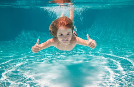 Foto de Niño nadando bajo el agua con los pulgares arriba. Niño bajo el agua nadar bajo el agua. Niño nadando y buceando bajo el agua en la piscina. Vacaciones de verano en familia con niños. Actividades subacuáticas para niños - Imagen libre de derechos
